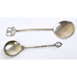 A pair of Arts and Crafts white metal spoons with pierced terminals and beaten bowls,