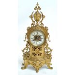 An early 20th century brass mantel clock with pierced ornate case and circular dial set with Roman