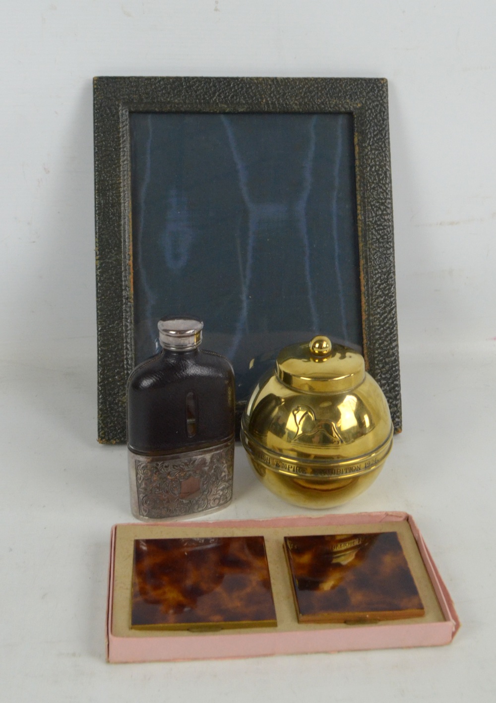 A hip flask with glass body and stitched leather upper section, a photograph frame,