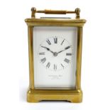 A late 19th century brass carriage clock with swing loop handle above rectangular white enamel dial