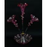 A Victorian cranberry tinted glass three branch epergne with wavy rims above crimped bowl,