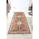 A Bokhara rug on orange ground, 290 x 124cm.