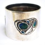 An Edwardian hallmarked silver Arts and Crafts enamel decorated napkin ring set with three panels