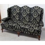 An Edwardian-style three-seat sofa with deep scrolling back to scrolling arms,