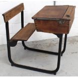 An early-to-mid 20th century metal-framed school desk with wooden bench seat and writing slope