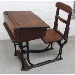 An early 20th century cast iron framed oak school desk with flip-up seat and lidded writing slope