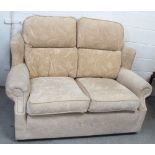A beige and cream floral upholstered two-seat sofa, high back to scrolling arms to castors,