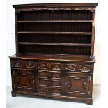 A reproduction oak three-shelf dresser with an arrangement of six drawers and two cupboard doors,