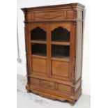 A reproduction freestanding bookcase with two glazed doors above small drawers (one pane of glass