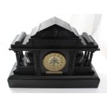 A large architectural black slate mantel clock with Grecian pediment surmounting a figural frieze