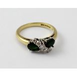 An 18ct chip diamond and emerald crossover ring set with two teardrop shaped emeralds,