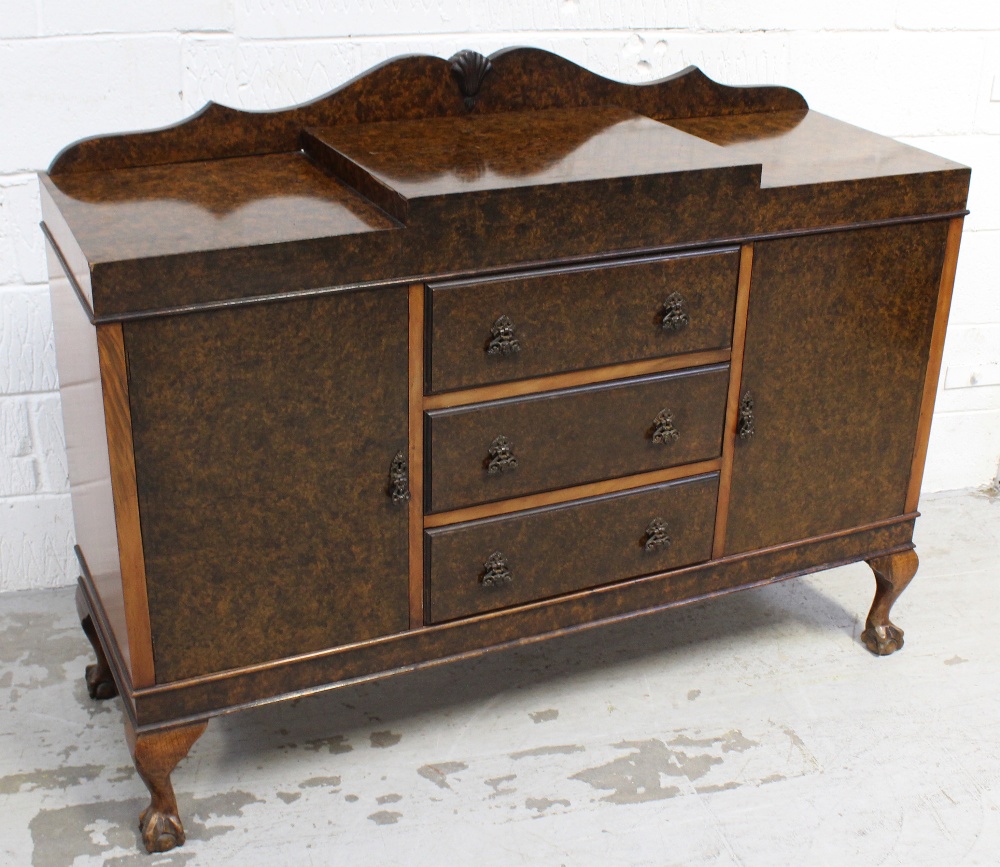 A walnut sideboard with three central drawers flanked by doors, on ball and claw feet, width 134cm.