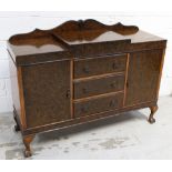 A walnut sideboard with three central drawers flanked by doors, on ball and claw feet, width 134cm.