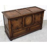 A late 19th/early 20th century oak coffer, three shaped panels over two smaller panels to bun feet,