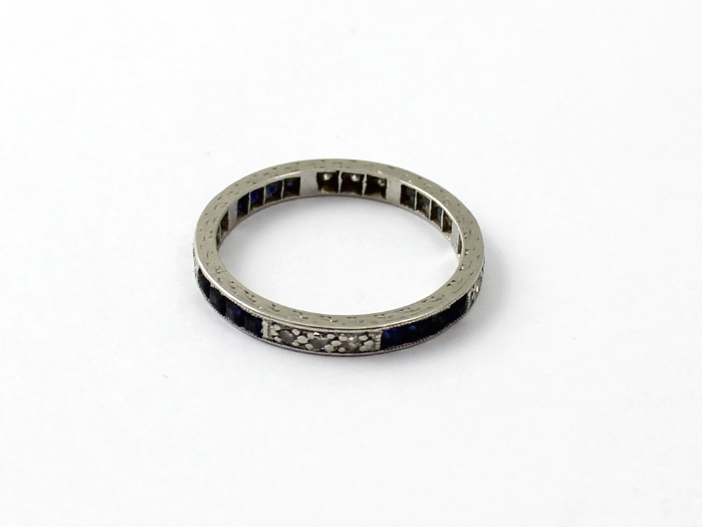 A chip diamond and sapphire unmarked white metal full eternity ring, size L, approx 2.5g.