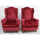 A pair of early 20th century upholstered wing-back armchairs on ball and claw feet (2).