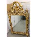 A Victorian ornate gilded wall mirror with laurel, urn and floral decoration to the top, to swag,