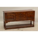 A reproduction oak dresser with three central drawers flanked by doors above a pot board base,