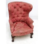 An upholstered late 19th century wing back armchair raised on cabriole front legs.