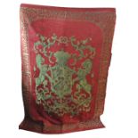 A modern chenille throw with armorial motifs on red ground within foliate scroll border,