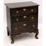 A carved oak chest of three drawers raised on square sectioned cabriole legs, width 77cm.