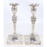 A matched pair of hallmarked silver Neo-Classical style candlesticks with embossed decoration to