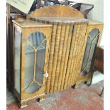 A 1930s walnut display cabinet with shaped central section flanked by glazed cupboard doors,