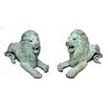 A pair of decorative cast metal garden lions in recumbent pose, height 75cm.