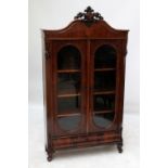 A 19th century Dutch mahogany bookcase with carved arched pediment above twin glazed doors and