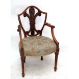 An Edwardian mahogany Hepplewhite style elbow chair with carved fleur-de-lis shield shaped back,