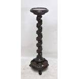 A Victorian carved mahogany torchère with foliate decoration, wrythen column and three paw feet,