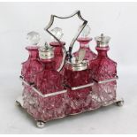 An early 20th century electroplated framed six piece cruet stand with clear and cranberry tinted