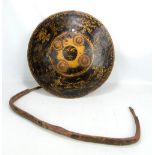 An Indian lacquered hide dahl with stylised gilt decoration, the reverse with four iron rings,