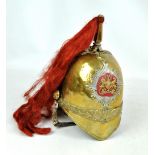 A brass helmet with applied Royal crest to front, red plume and ringlet chin strap,
