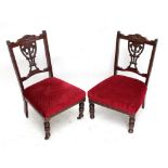 A pair of Edwardian walnut nursing chairs on ring turned supports.