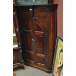 A George III oak two door flat fronted hanging corner cupboard, with H-shaped brass hinges,