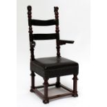An unusual Continental oak studded leather upholstered open elbow chair with carved figural finials,