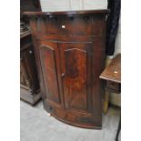 A 19th century mahogany bowfronted corner cupboard with pair of doors enclosing four shelves above