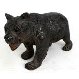 A Black Forest carved bear with inset glass eyes, length approx 28cm.