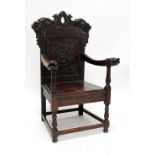 A Victorian carved oak panelled back elbow chair with stylised dolphin top rail above mask back,