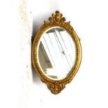 An oval bevelled wall mirror in ornamental gilt frame, height 93cm.