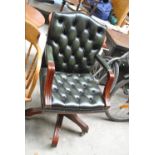 A green leather buttoned and studded revolving desk chair on castors.