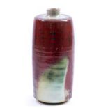 DEREK DAVIS (1926-2008); a stoneware bottle covered in mottled copper red glaze, painted mark,