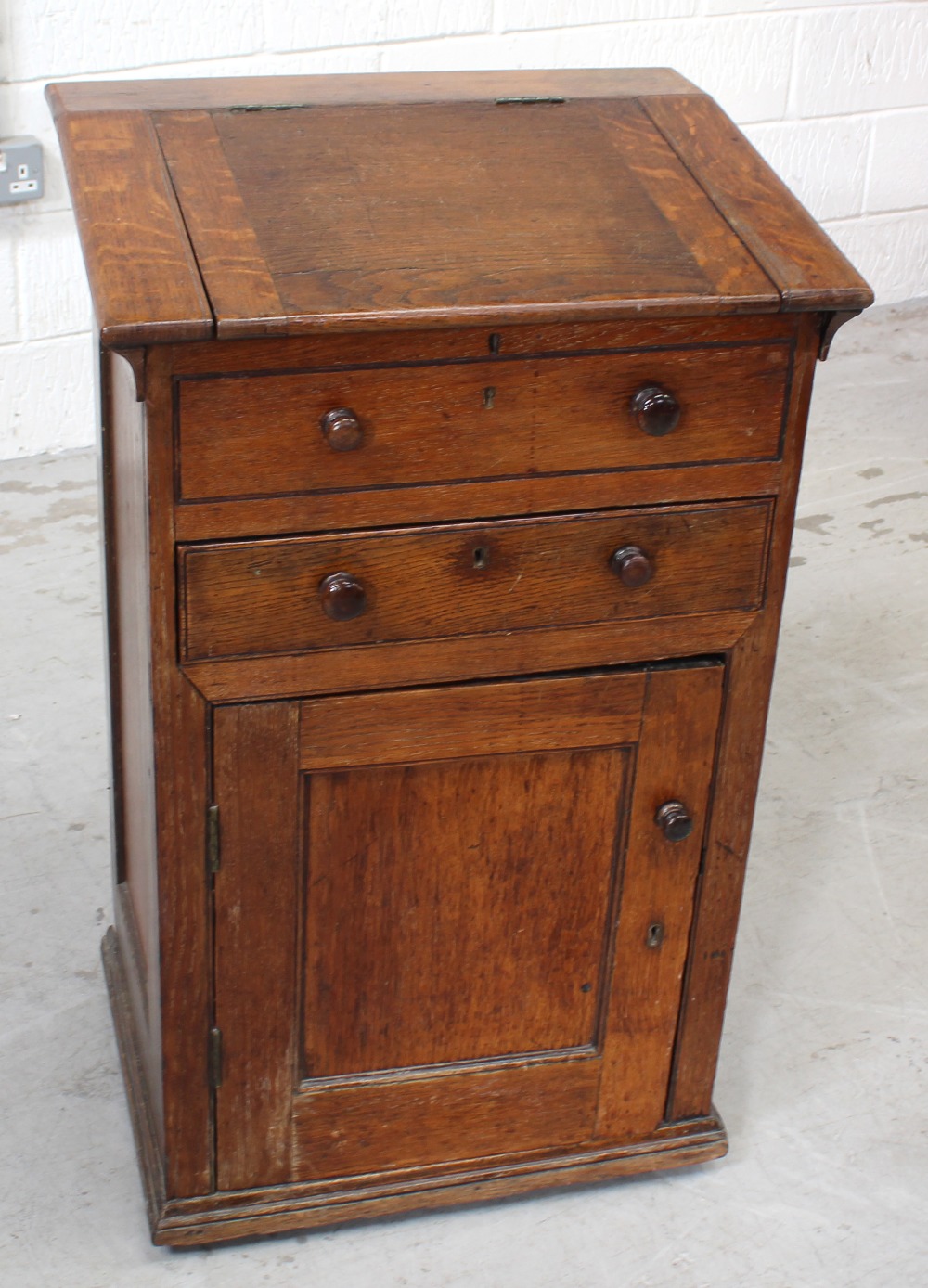 A Victorian oak clerk's desk with hinged top above dummy drawer and one working drawer above