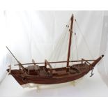 A scratch-built teak model dhow with single mast and no sails, presented on wooden stand, 67 x 96cm.