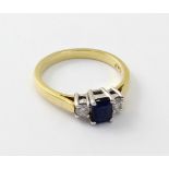 An 18ct gold ladies' ring, central emerald cut blue sapphire and diamond to either side, size M,