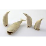 A family of three penguins of graduating size carved from whales' teeth and a whale,