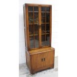 A 1930s solid oak Arts and Crafts style elevated bookcase with quarter glazed twin doors with two