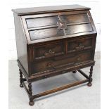 An early 20th century oak panel bureau with mechanical lopers and fitted interior over a two-drawer