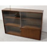 A 1960s Sapele mahogany glass front floor standing bookcase with sliding doors, width 122cm.